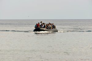 Crowded inflatable boat with many people wearing life jackets at sea the open ocean ahead.