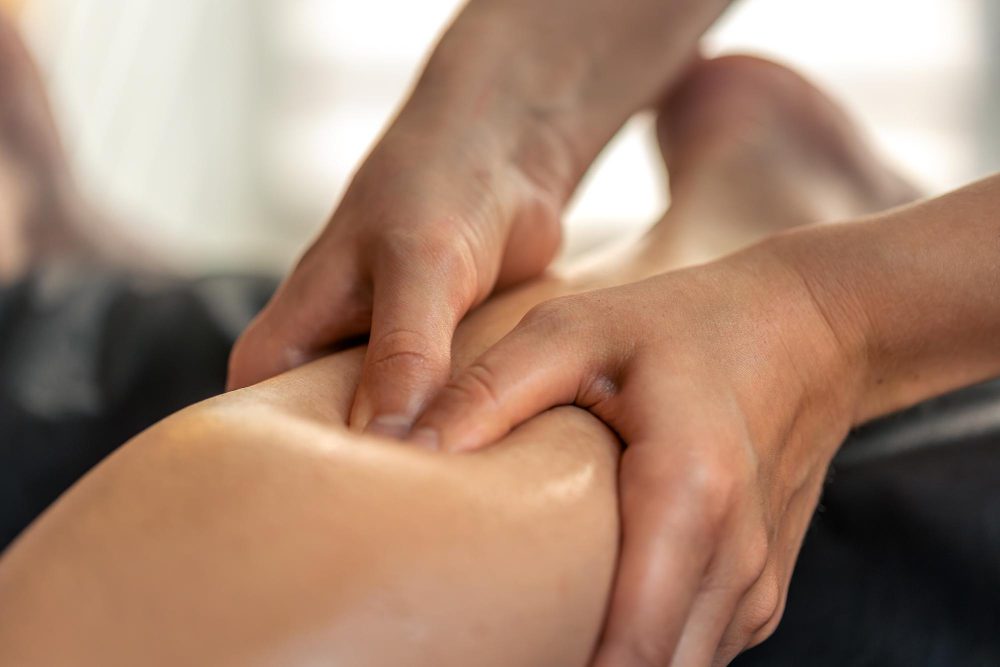 Close-up of hands massaging a bare ankle.