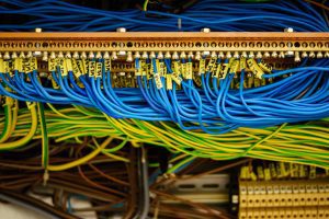 Close-up of a network patch panel with blue and yellow Ethernet cables neatly plugged into connectors, cables bundled in a data rack.